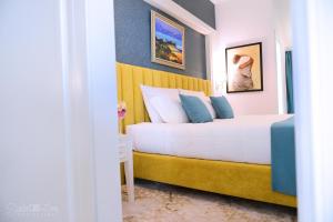 a bedroom with a white bed with a yellow headboard at ART Hotel Tirana in Tirana