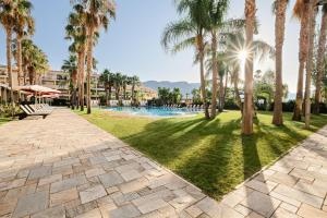 a park with palm trees and a swimming pool at Envía Almería Apartments Spa & Golf in Aguadulce