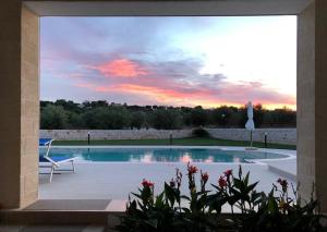 una piscina con sedia e tramonto di I Trulli di Gina Appartamento Trullo 6 persone a Monopoli