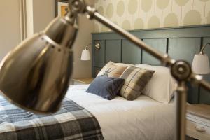 a close up of a bed with a lamp on it at The Evenlode Hotel in Witney