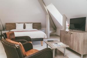 a bedroom with a bed and a tv and a chair at Terres de France - Appart'Hotel le Splendid in Allevard