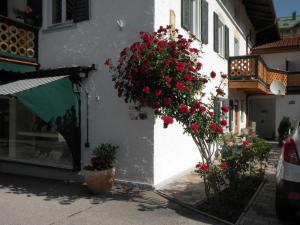 un edificio con flores rojas a un lado. en Ferienwohnungen Rosenhof, en Tegernsee