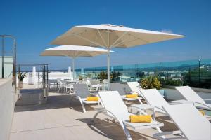 eine Gruppe weißer Stühle und ein Regenschirm auf einem Dach in der Unterkunft Hotel Seasun Aniram in Playa de Palma