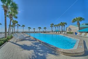 a swimming pool with chairs and palm trees at Dunes of Panama in Panama City Beach