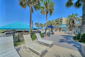a row of white chairs and palm trees on a sidewalk at Dunes of Panama in Panama City Beach