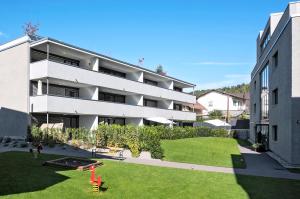 an apartment building with a lawn in front of it at Relaxed Urban Living - Aparthotel und Boardinghouse in Dornbirn