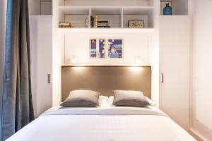 a small bedroom with a bed with white sheets and pillows at Design & New Loft in heart of Paris in Paris