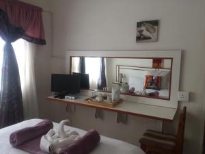 ein Schlafzimmer mit einem Spiegel, einem Bett und einem Schreibtisch in der Unterkunft Hae Bed and Breakfast in Leribe