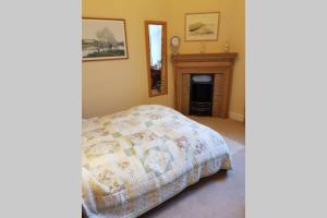 ein Schlafzimmer mit einem Bett und einem Kamin in der Unterkunft Woodburn Terrace, Morningside, Edinburgh in Edinburgh