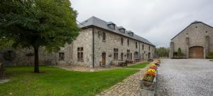 un grand bâtiment en pierre avec des fleurs devant lui dans l'établissement B&B Ferme Château de Laneffe, à Laneffe