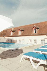 een gebouw met een zwembad met blauwe stoelen bij Terres de France - Appart'Hôtel La Roche-Posay in La Roche-Posay
