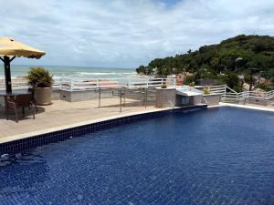 a swimming pool with a view of the ocean at Pipa's Bay Apartamentos in Pipa