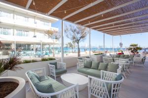 un patio en la playa con sillas y mesas en Grupotel Picafort Beach, en Can Picafort