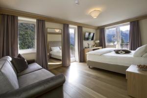 a hotel room with two beds and a couch at Hotel Lorenzetti in Madonna di Campiglio