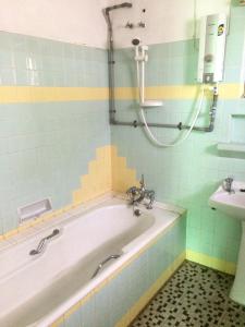 a bathroom with a bath tub and a sink at The Fairview Guesthouse in Kuching