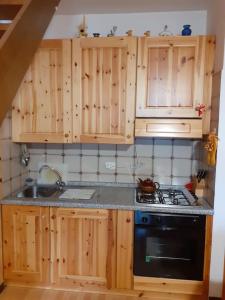 een keuken met houten kasten, een fornuis en een wastafel bij Accogliente e confortevole appartamento a Tarvisio in Tarvisio