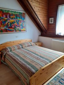 1 dormitorio con 1 cama con una pintura en la pared en Accogliente e confortevole appartamento a Tarvisio, en Tarvisio