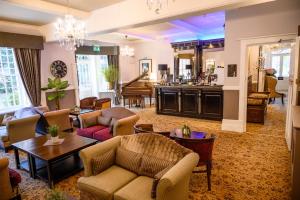 ein Wohnzimmer mit Sofas und Tischen sowie eine Küche in der Unterkunft Langtry Manor Hotel in Bournemouth