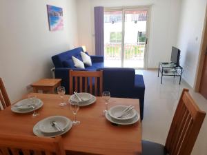 une salle à manger avec une table, des assiettes et des verres à vin dans l'établissement Ground floor One Bedroom Apartment, Vanessa Complex, à Peyia