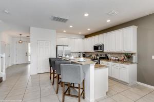 a kitchen with white cabinets and a island with bar stools at Veranda Palms 8 Bedroom Home with Pool - 1722 in Kissimmee