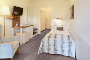 a room with a bed and a desk and a tv at Hotel Ancora in Timmendorfer Strand