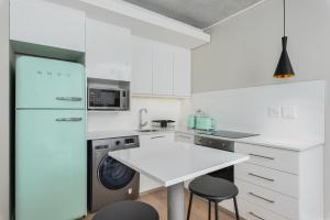 eine weiße Küche mit einem Kühlschrank und einem Tisch in der Unterkunft The Docklands Luxury Apartments in Kapstadt