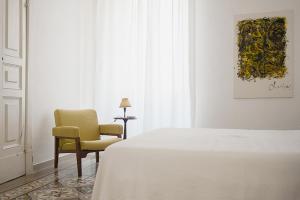 a white bedroom with a bed and a chair at Dimora Rugiada in Chieti