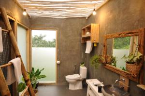 ein Badezimmer mit einem WC, einem Waschbecken und einem Spiegel in der Unterkunft Manulalu Jungle in Bajawa