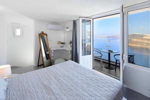 a bedroom with a bed and a view of the ocean at Suites of the Gods Cave Spa Hotel in Megalokhori