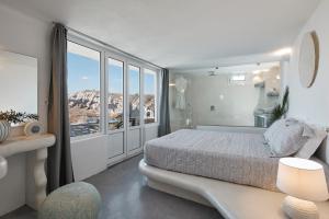 a bedroom with a bed and a large window at Suites of the Gods Cave Spa Hotel in Megalokhori