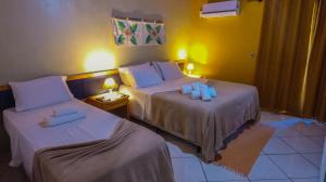 duas camas num quarto de hotel com almofadas azuis em Pousada Aldeia Portuguesa em Porto Seguro