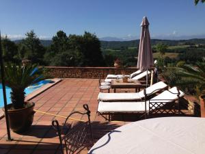 a patio with chairs and an umbrella and a pool at Annie chambres hôtes in Cassagnabère-Tournas