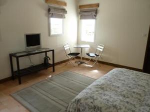 Schlafzimmer mit einem Bett, einem Schreibtisch und einem TV in der Unterkunft Domaine du Chêne Crucy in Liré