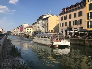 un barco flotando río abajo en una ciudad en Lovelyloft - Alzaia Naviglio, en Milán