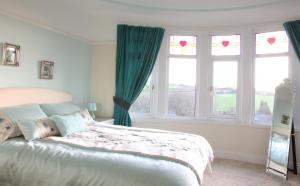 a bedroom with a large bed and two windows at Langdale House in St Austell