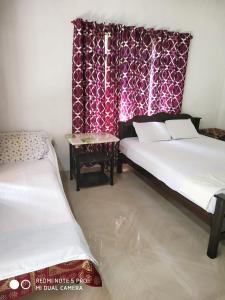 two beds in a room with red curtains and a table at Munroe Heritage Inn in Munroe Island