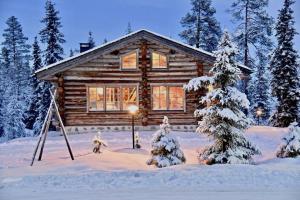 eine Blockhütte im Schnee mit einem Weihnachtsbaum in der Unterkunft VILLA KELO in Ruka