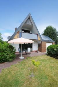 Cette maison dispose d'une terrasse avec une table et un parasol. dans l'établissement Ferienhaus Leevje, à Neuharlingersiel