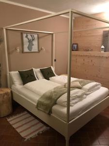 - une chambre avec un lit à baldaquin et des draps blancs dans l'établissement Casa Benassi Rooms, Apartament & Suite con Piscina panoramica e Wellness, à Riolunato