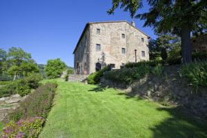 an old stone building on a hill with green grass at Villa Ruffignano in Cortona