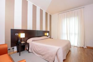 una camera con letto e parete a righe di Hotel Aleramo ad Asti