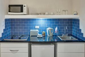 a kitchen with a sink and a blue tile wall at Butterfly Beach Hotel in Christ Church