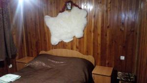 a bedroom with a bed and a white blanket on a wooden wall at Rosinka in Yaremche