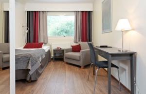 a hotel room with a bed and a desk and a chair at Hotel Nuuksio - Conferences and events in Espoo