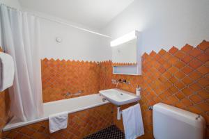 uma casa de banho em azulejo laranja com um lavatório e um espelho. em LAAX Homes - Casa Coray em Laax