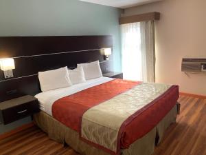 A bed or beds in a room at Olive Tree Inn & Suites