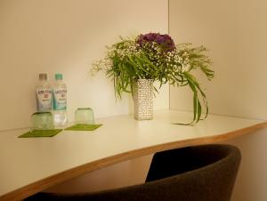 a vase of flowers on a table with bottles of water at Trafohaus am Kaiserbahnhof in Brühl