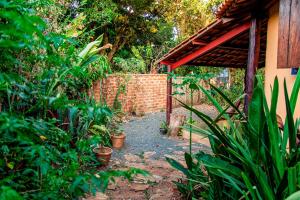 un jardín con una pared de ladrillo y un camino en Chalé Ipê - Jatobá, en Alto Paraíso de Goiás