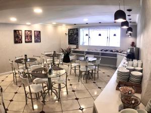 a restaurant with tables and chairs and a kitchen at Terrazas Hotel in Curitiba