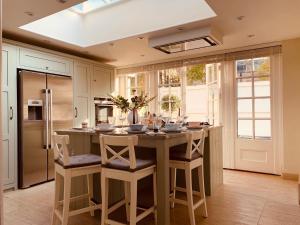 una cocina con una gran isla de cocina con taburetes en The Midsummer Common - Modern & Spacious 2BDR House with Garden, en Cambridge